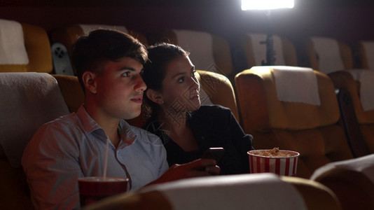 男人在手机上玩游戏他让的女朋友烦恼并干扰看电影图片