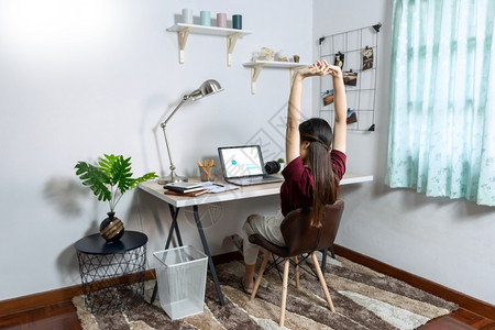 在室内客厅办公作为自由职业者电子协调工作远程或在家以外的概念而使用笔记本电脑和文件的年轻有吸引力漂亮亚洲女图片