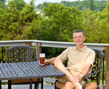 中年男子坐在甲板上的铸铝在后院喝杯啤酒图片