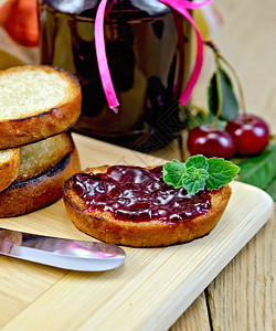 烤面包片一杯加樱桃果酱的玻璃罐木板上刀图片