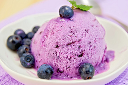 蓝莓冰淇淋夹薄荷叶碗里有浆果底紫布和木板图片