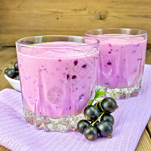 紫色餐巾纸上两个低杯子罐中黑色的奶昔木板上有浆果卷子的碟背景图片