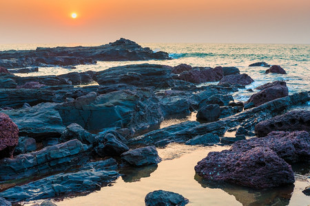 日落时美丽的海景和岩石岸图片