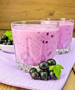 紫色餐巾纸上两个低杯子罐中黑色的奶昔木板背景上有浆果卷子的碟背景图片