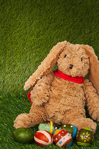 兔子坐在绿色草地上与一群多彩的鸡蛋可以用作背景庆祝快乐的复活节图片