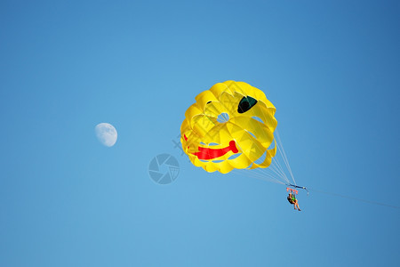 一艘降落伞在海上被拖走背面是蓝色的天空左边是月亮背景图片