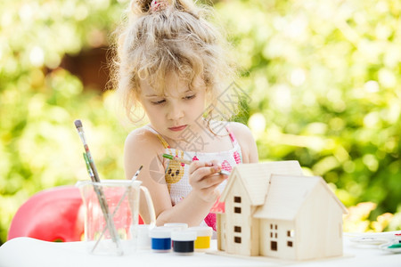 小女孩绘画肖像木制房屋模型夏季户外新的家庭概念图片