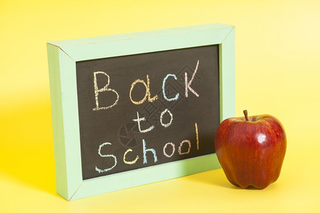 黄色背景上黑板写着回学校回到学校写在黑板上的红苹果上图片