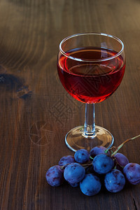 一杯红酒和黑木板上一串葡萄图片