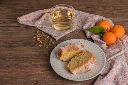 橘子蛋糕薄荷蛋糕片加糖粉和甘菊茶盘子上的蛋糕木板有新鲜的背景