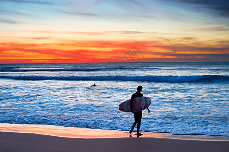 冲浪机在大日落时海滩上行走图片