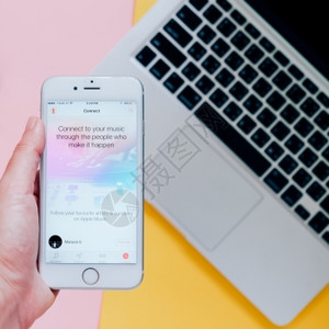 2016年月8日手持苹果iphone6显示苹果音乐应用程序并带有笔记本电脑背景苹果音乐是新推出的ibones音乐流服务图片