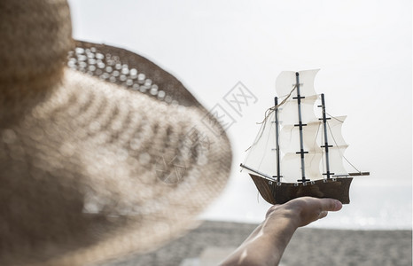 模特举着帆船在海边拍照图片