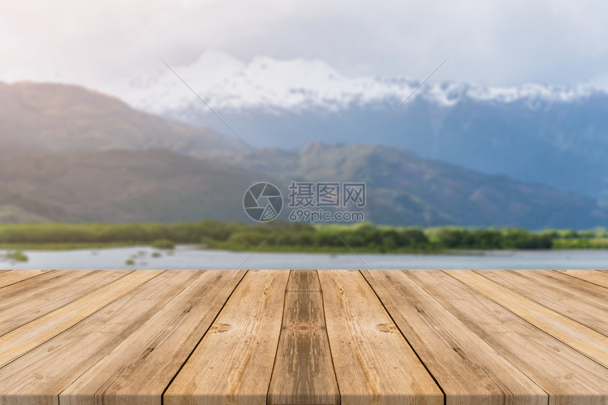 在模糊背景面前的木板空桌在森林山底的模糊湖面上看到褐色木板可以模拟显示或调换产品图片