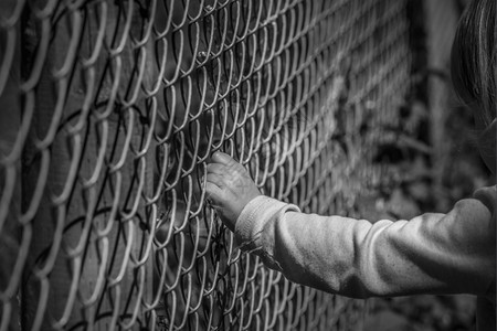 黑白一幅小女孩手抓着铁栅栏的画面黑色高清图片素材