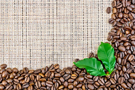 咖啡和咖啡豆黑咖啡豆框架和棕粗织布上的叶子背景