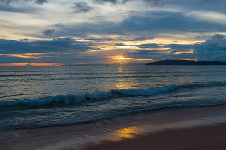 海浪在夜晚美丽的日落沙滩上滚动图片