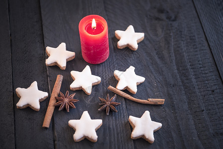 土制肉桂和坚果饼干恒星形状中间配有装饰香料在蜡烛下黑木板上图片