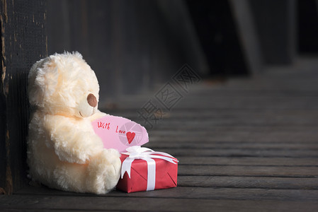 带着一张可爱的泰迪熊拿着纸条的礼物上面写着爱和红礼盒图片