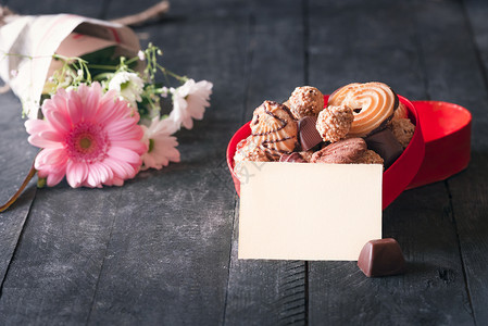一张空纸贴着一张红盒的贺卡想法上面装满了饼干巧克力和一束鲜花背景图片