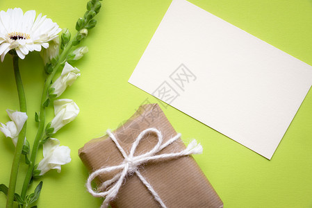 贴纸条的贺卡想法上面贴着白花和礼品盒包着棕色纸绑麻绳和弓并印在绿色背景上背景图片