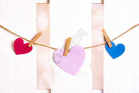 情人节主题图像中间有一个大粉红色的心边上一个红色和蓝的用纸做绑在绳子上带木制剪片图片