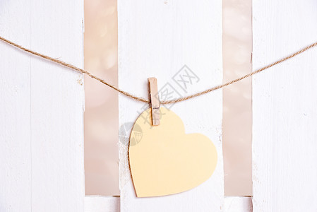 纸条心形绑在有木片的线条上在白木栅栏背景上一种爱沟通贺卡的概念图片