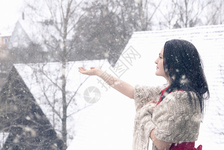 身着红裙子的黑发年轻女人手抓雪花图片