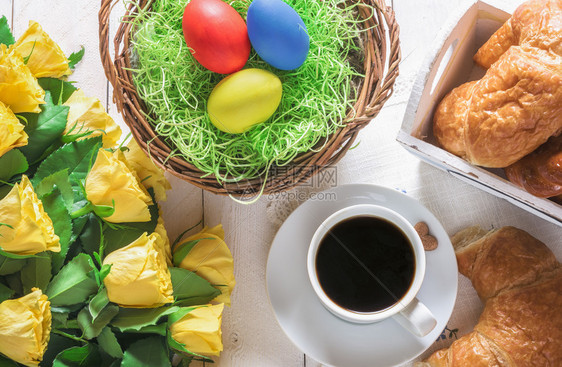 东边的早上安排一杯咖啡篮子鸡蛋新鲜烤牛角面包和一束美丽的黄玫瑰花束图片