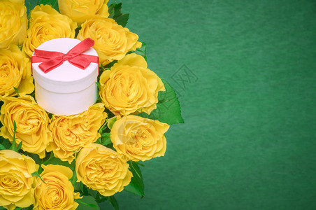 美丽的黄玫瑰花束和可爱的白色小礼物上面绑着红丝带在中间鞠躬图片