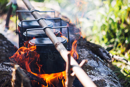 在森林里露营游行一个准备食物的酱锅冒险旅游烹饪着火活在森林里旅行概念图片