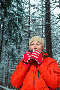 在冬季森林里带着一杯热茶的金属子年轻美女图片