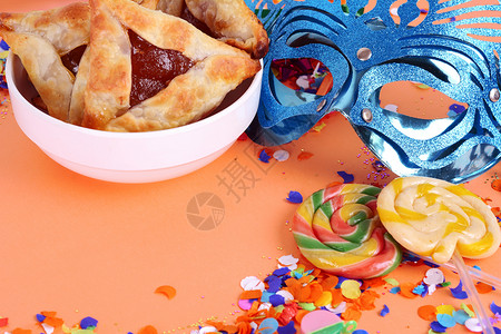 带有嘉年华面罩党服和Hamntsche饼干的彩虹背景顶部视图图片