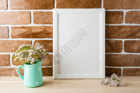 白色框架的粉红花朵放在砖墙附近的薄荷瓶中空框架用于演示设计现代艺术的模板白色框架在砖墙附近图片
