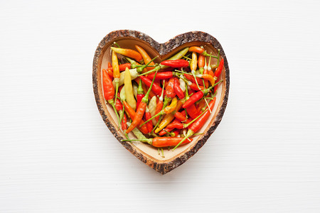 木菜心形的多彩辣椒木菜心形的多彩辣椒白色的木菜心形多彩辣椒图片