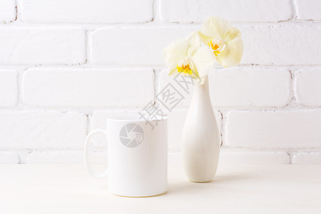 白色咖啡杯用软黄兰花在瓶中空白杯用色咖啡用软黄色兰花在瓶中图片