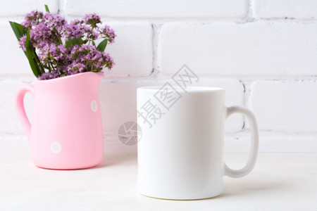 白色咖啡杯在polkadt粉红皮带紫色花朵白咖啡杯在polka点粉红生锈的花瓶里紫色田地花朵空杯子在设计宣传上模拟图片