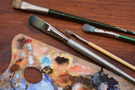 艺术家配有多彩油色画笔和木制背景的调色板艺术概念图片