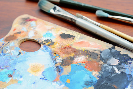 艺术家配有彩色油画笔和木背景上的油漆刷子调色板艺术概念配有彩色油画笔和漆刷子的调色板图片