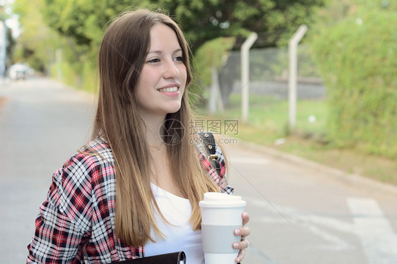 在街上拿着纸咖啡杯的美女肖像城市的风景户外图片