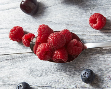 樱桃蓝莓甜的果子放在灰色背景的汤匙上平坦素食理念大勺子红新鲜的草莓灰色背景的背景