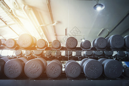 体育俱乐部的一排哑铃在健身房锻炼康的概念图片