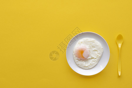 白盘上单煎蛋和黄勺子色背景图片