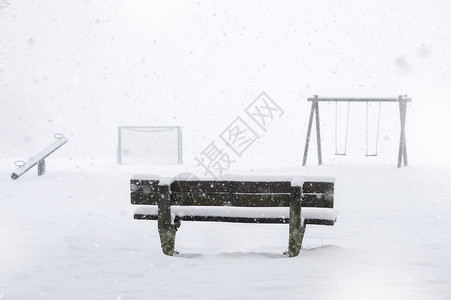 冰冷的冬季形象有木凳和操场四周被雪覆盖同时下在德国的天空上下雪背景图片