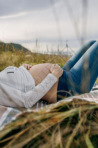 孕妇躺在在草地上抚摸腹部图片