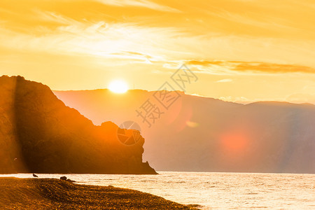 明亮的太阳美丽岩石和海洋黎明时美丽的风景图片
