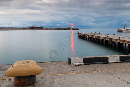 黄昏时海岸有明亮红光的堤岸码头和灯塔图片