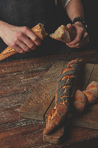 男人和手握被分割的袋式面包在深木背景上半径男手打破了袋式面包板背景图片