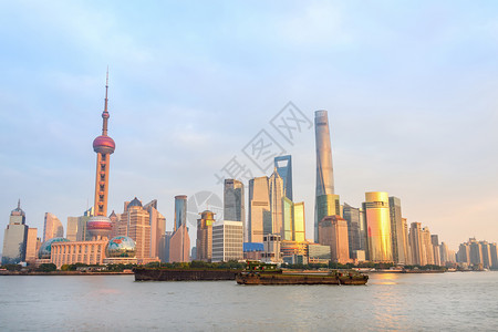 日落时有现代建筑的上海天线城市堤岸的生锈驳船图片