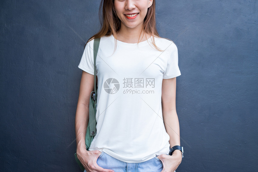 身穿白t恤的棕色长头发亚洲时装女孩站在街上身穿头服装的女站在灰色墙壁背景上图片